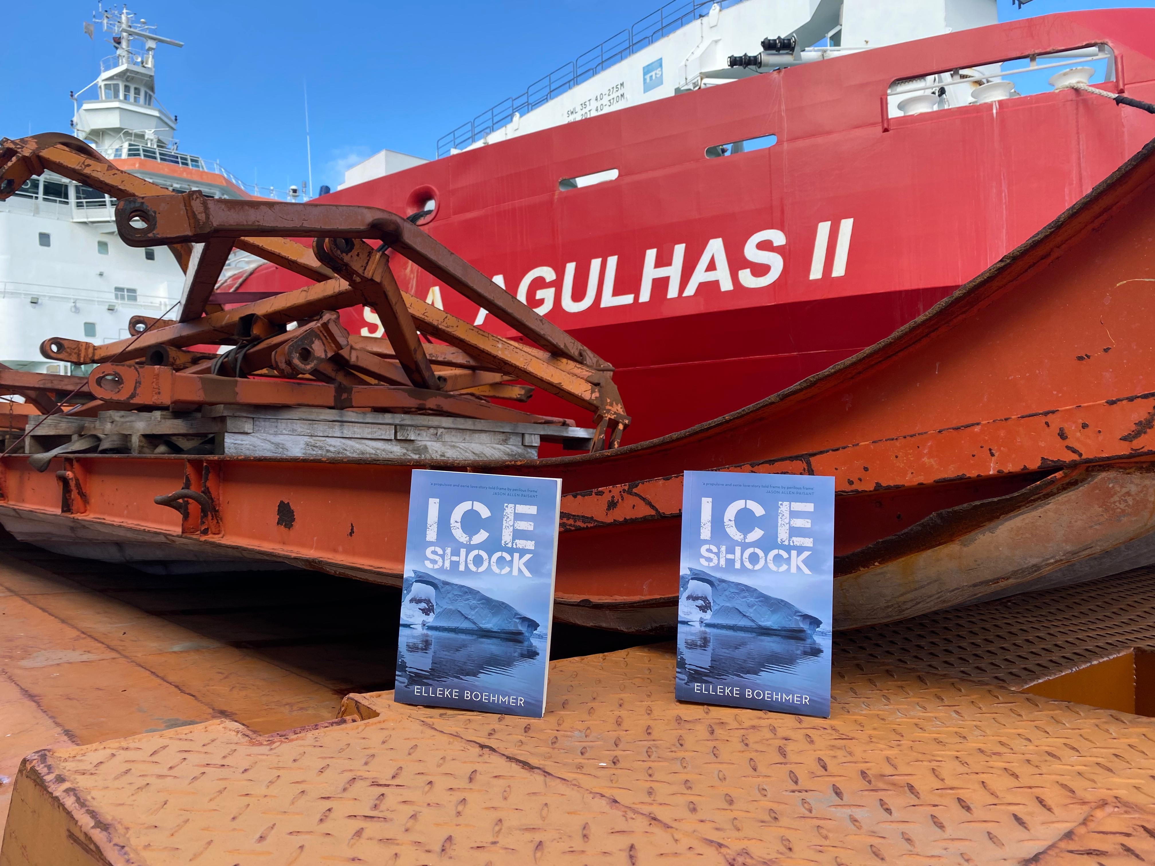Two copies of the novel Ice Shock are visible in front of the ship S. A. Agulhas II